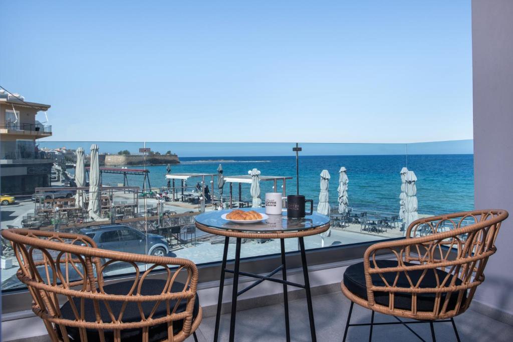 a table and chairs on a balcony with a view of the ocean at Blue Balcony Boutique Beachfront Suite with Private Parking in Chania Town