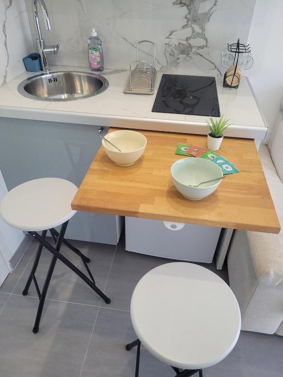 - une cuisine avec 2 bols sur une table en bois avec 2 tabourets dans l'établissement Studio dans maison familiale proche Paris et Disney, à Noisy-le-Grand