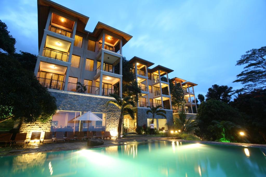 un hôtel avec une piscine en face d'un bâtiment dans l'établissement Randholee Resort & Spa, à Kandy