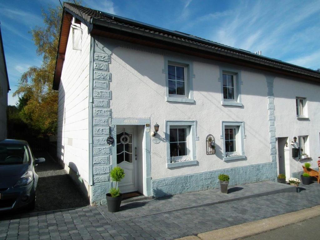 a white house with a car parked in front of it at Carmius - Back to simple life in Burg-Reuland