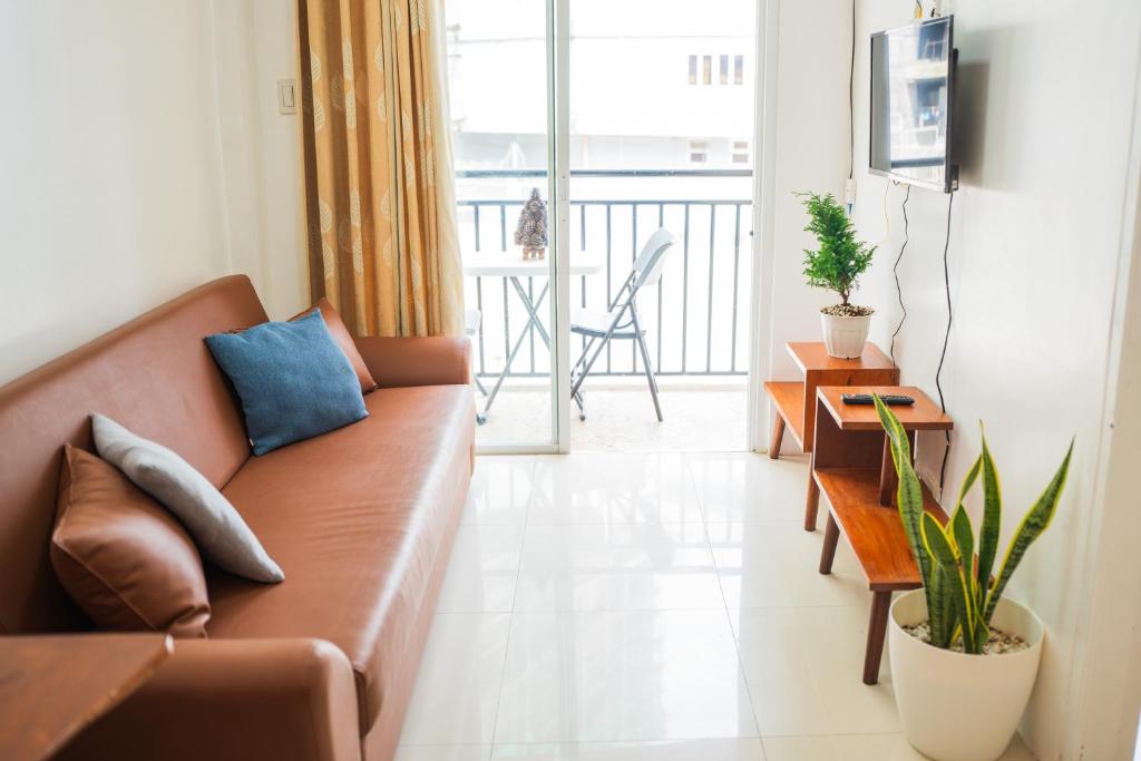 uma sala de estar com um sofá castanho e uma varanda em Burnham Hill 2BR Condo em Baguio
