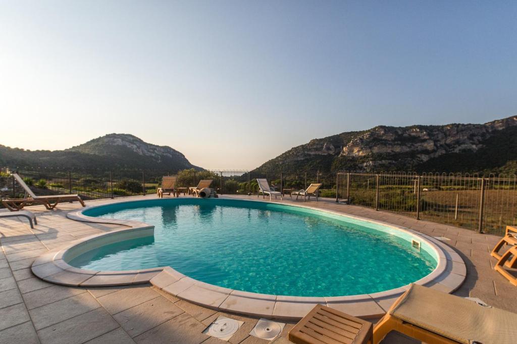 a large swimming pool with chairs and mountains in the background at Auberge Lustincone in Patrimonio