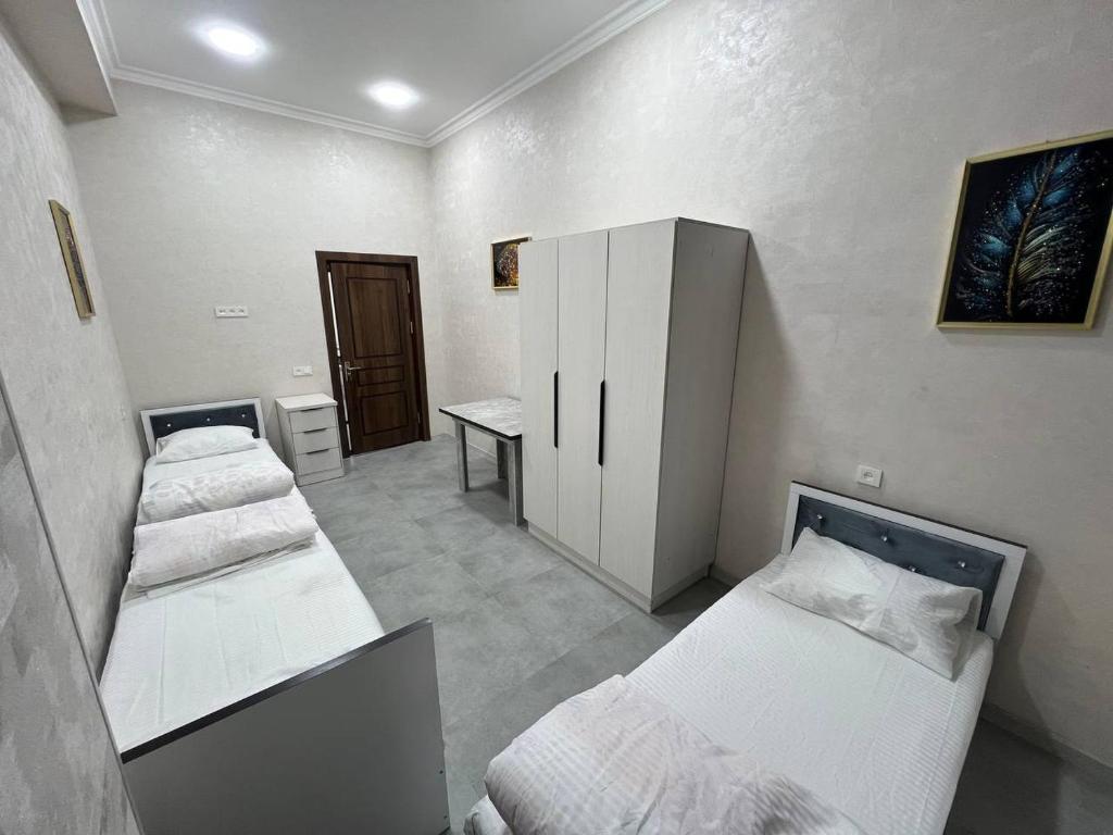 a room with three beds and a desk in it at Hostel Art Sergeli in Stantsiya Kyzyl-Tukumachi