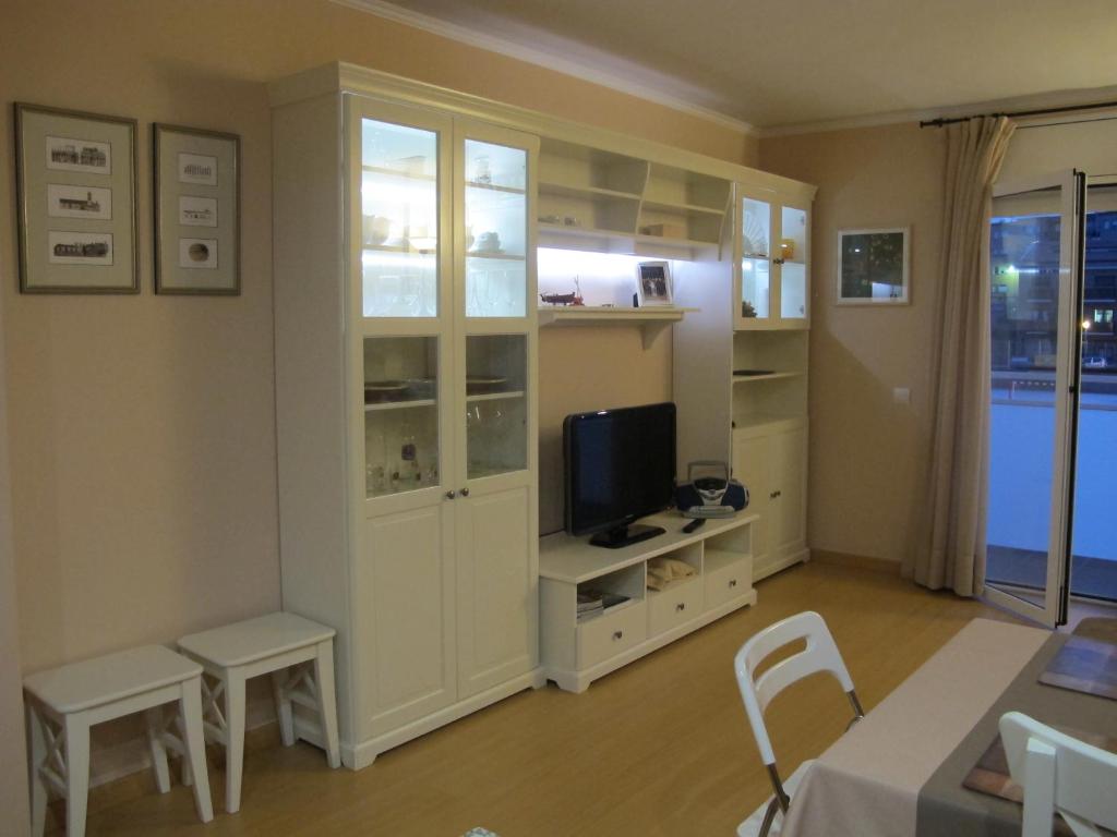 Nice apartment in Costa Brava في بالافروجيل: غرفة معيشة فيها تلفزيون ودواليب بيضاء