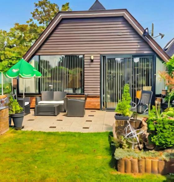 a patio with chairs and an umbrella in a yard at Spacious Nature Escape, house for 6 near Amsterdam & Sea in Opmeer