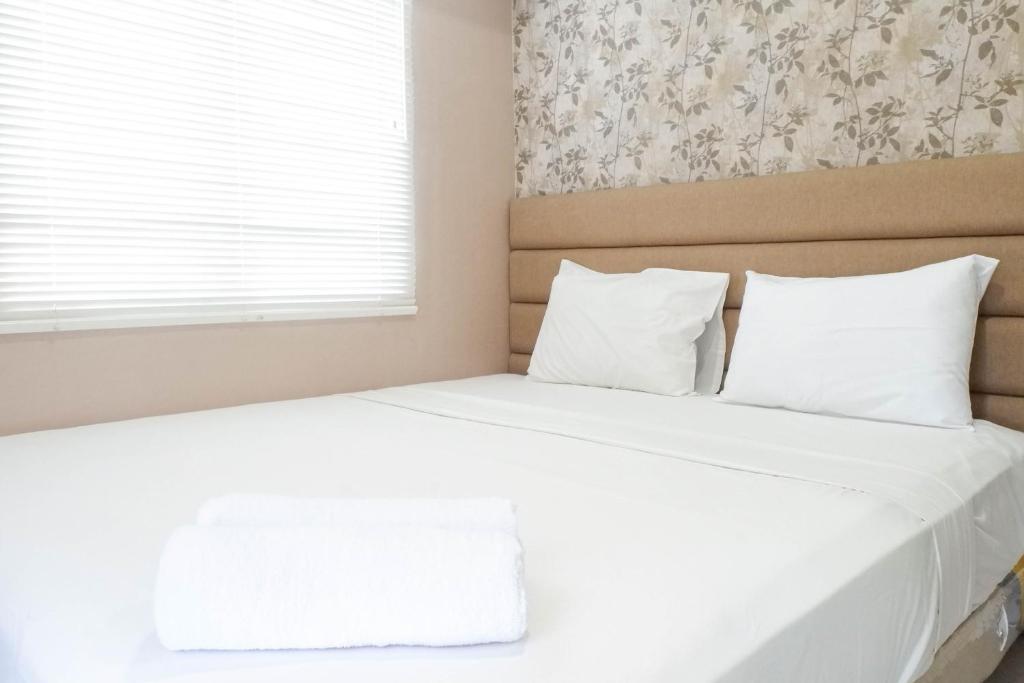 a white bed with white pillows and a window at Comfy and Modern Wonderful 2BR Apartment at Tanglin Supermall Mansion By Travelio in Surabaya
