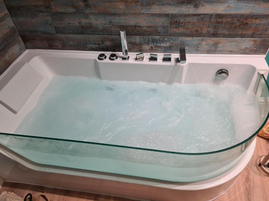La salle de bains est pourvue d'une baignoire remplie d'eau. dans l'établissement L'île Turquoise- Balnéo Privée I Relaxation, à Boulogne-sur-Mer
