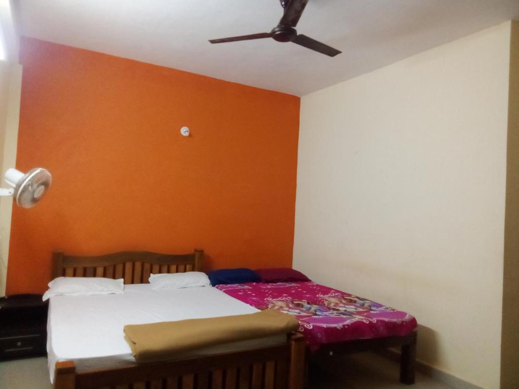 a bedroom with a bed and a ceiling fan at Ishwar Place Rooms and Cafe Gokarna in Gokarna