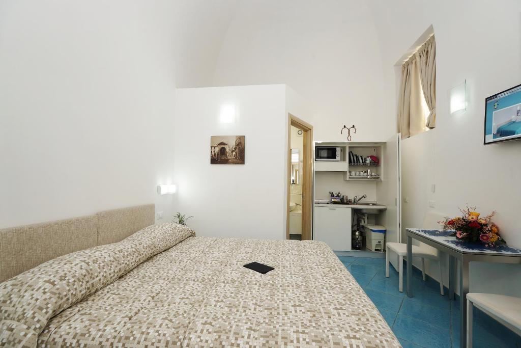 a bedroom with a bed and a desk and a kitchen at Sorrento Inn Funzionista in Sorrento