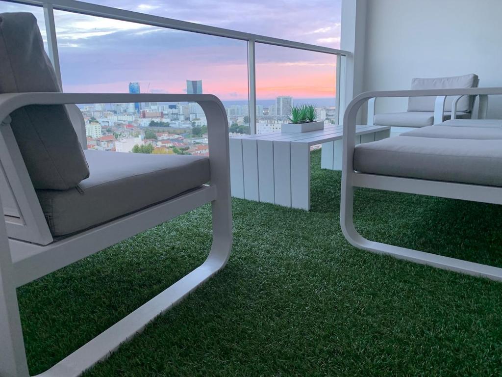 une pièce avec deux chaises et un balcon avec de l'herbe verte dans l'établissement Appartement standing tout confort vue mer, à Marseille