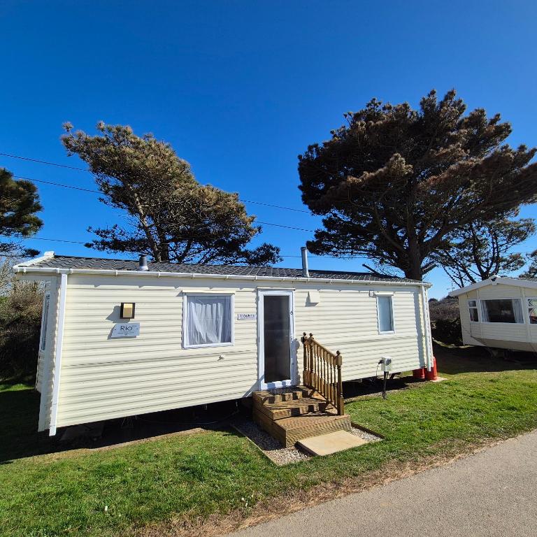 a white tiny house with a porch and stairs at Cosy Perranporth caravan, Cornwall in Perranzabuloe