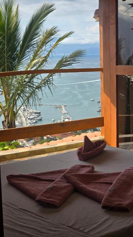 a view of a beach from a window with towels at Suite Pássaros in Ilhabela