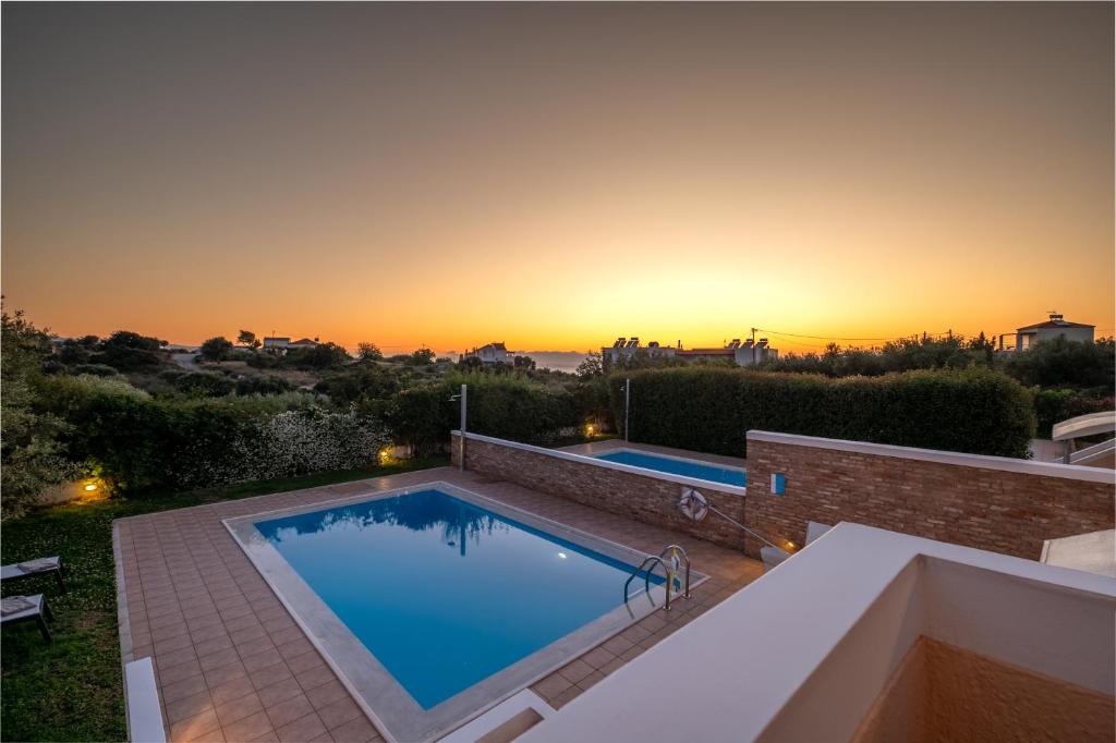 a swimming pool on the roof of a house with a sunset at Koralia's Villas in Chorafakia