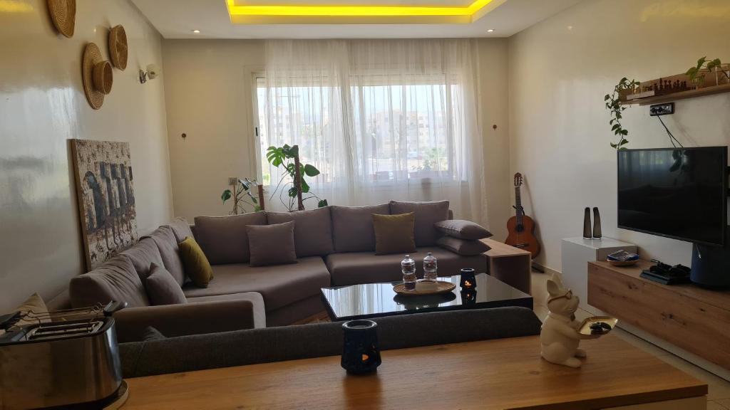 a living room with a couch and a tv at Private room in a shared apartment with pool in Agadir