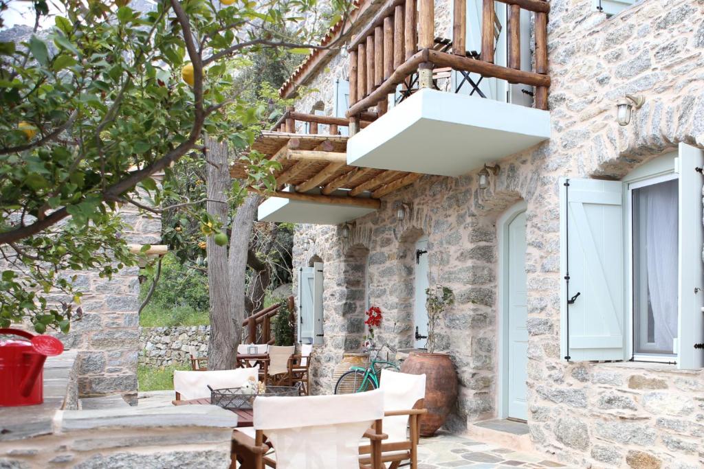 a patio of a house with white chairs and a balcony at Stone houses Areti 1 in Manganítis