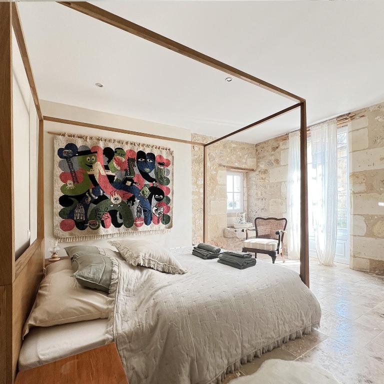 une chambre avec un grand lit et un tableau au mur dans l'établissement Gîte - LA CLOCHETTE, à Lugon et l’Ile du Carney