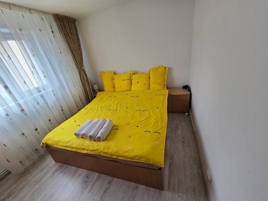 a bedroom with a yellow bed with yellow sheets and pillows at Apartament 2 camere Brazda lui Novac in Craiova