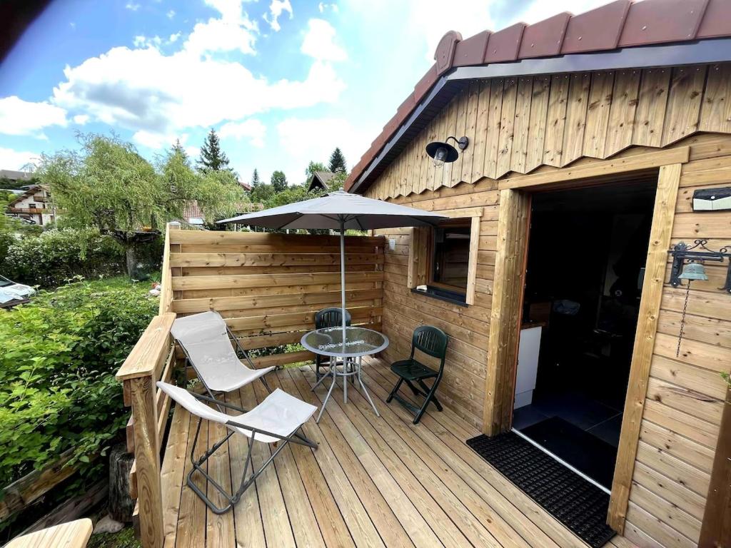 une terrasse avec une table, des chaises et un parasol dans l'établissement Le gîte du four à pain, à Xonrupt-Longemer