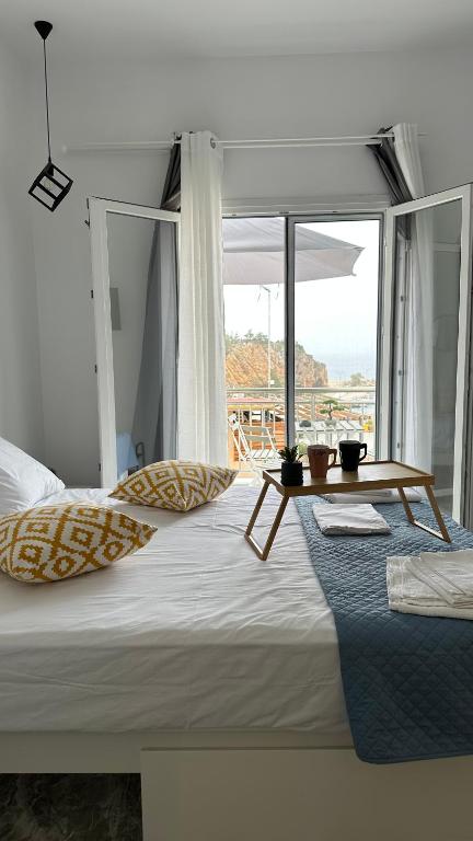 a bedroom with a bed with a table and a window at Pefki apartments in Limenaria