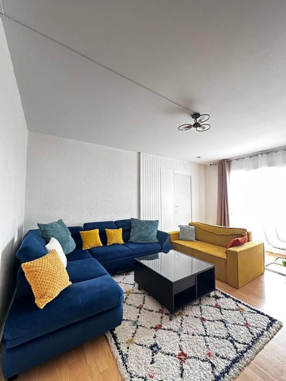 un salon avec un canapé bleu et un tapis dans l'établissement Mantes-la-Jolie Apartment 8p, à Mantes-la-Jolie