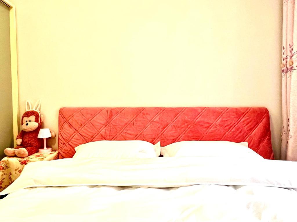 a bed with a red headboard and a teddy bear at Nicer Family in Leshan
