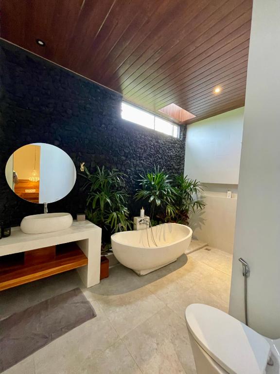 a bathroom with a tub and a mirror and plants at Puri Gia in Mambat