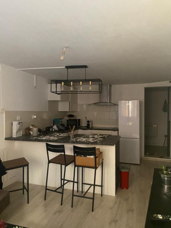 a kitchen with a counter and two chairs and a refrigerator at Petit nid au centre historique de Marvejols in Marvejols