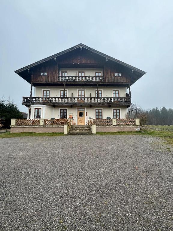 ein großes weißes Gebäude mit einem Holzdach in der Unterkunft Pension Huber in Fischbachau