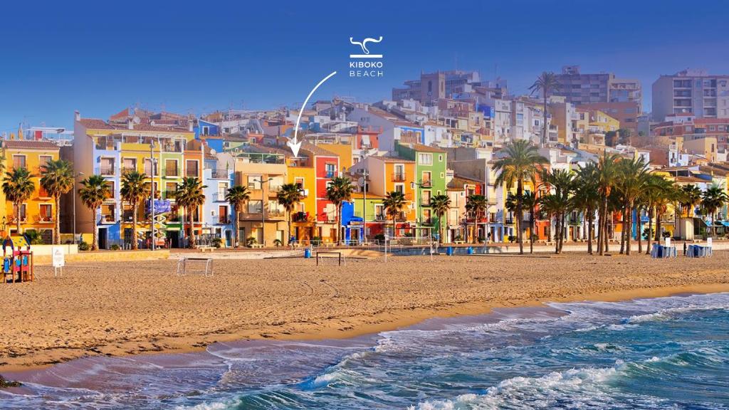 a view of a beach with palm trees and buildings at Kiboko Beach in Villajoyosa