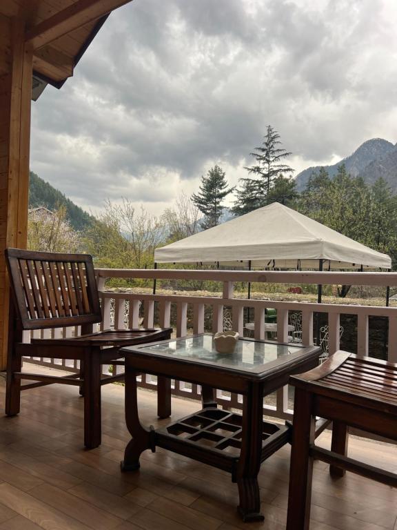 a porch with two benches and a gazebo at Brahma Cottages in Kasol