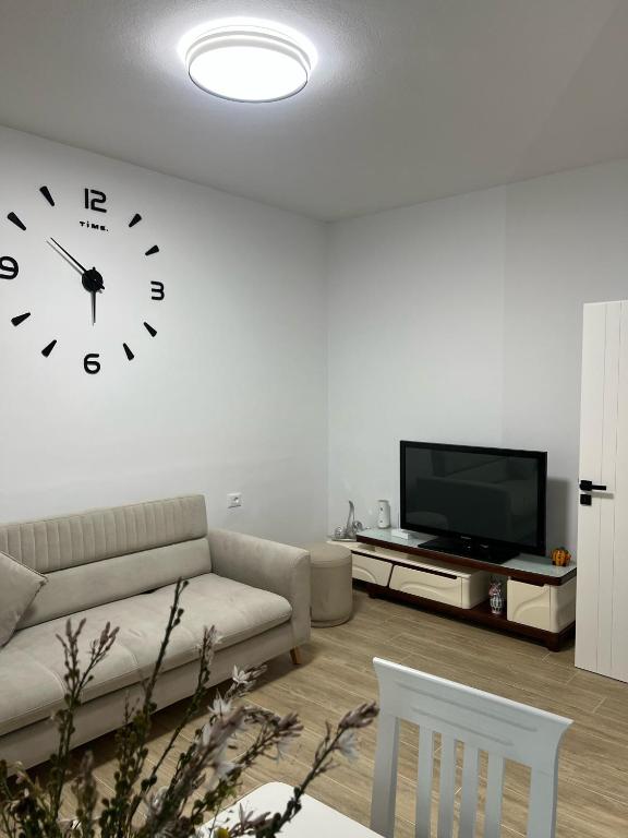 a living room with a couch and a clock on the wall at Huna Apartment in Sarandë