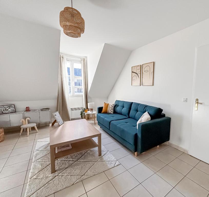 un salon avec un canapé bleu et une table dans l'établissement FairyHome Parking Privé Proche Disney, à Magny-le-Hongre