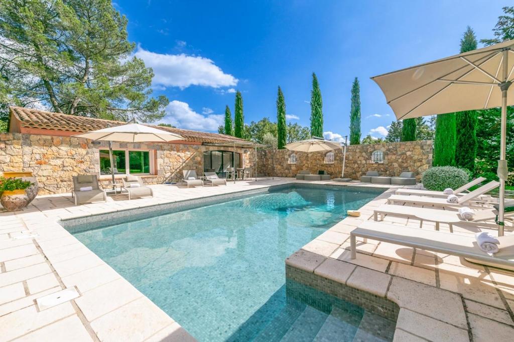 a swimming pool with chairs and an umbrella at Beautiful property near Fayence in Saint-Paul-en-Forêt