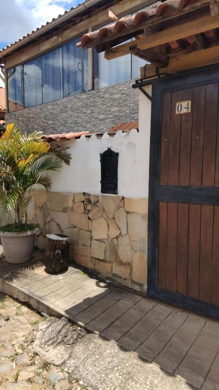 a house with a wooden door and a stone wall at casa da meg in Tiradentes