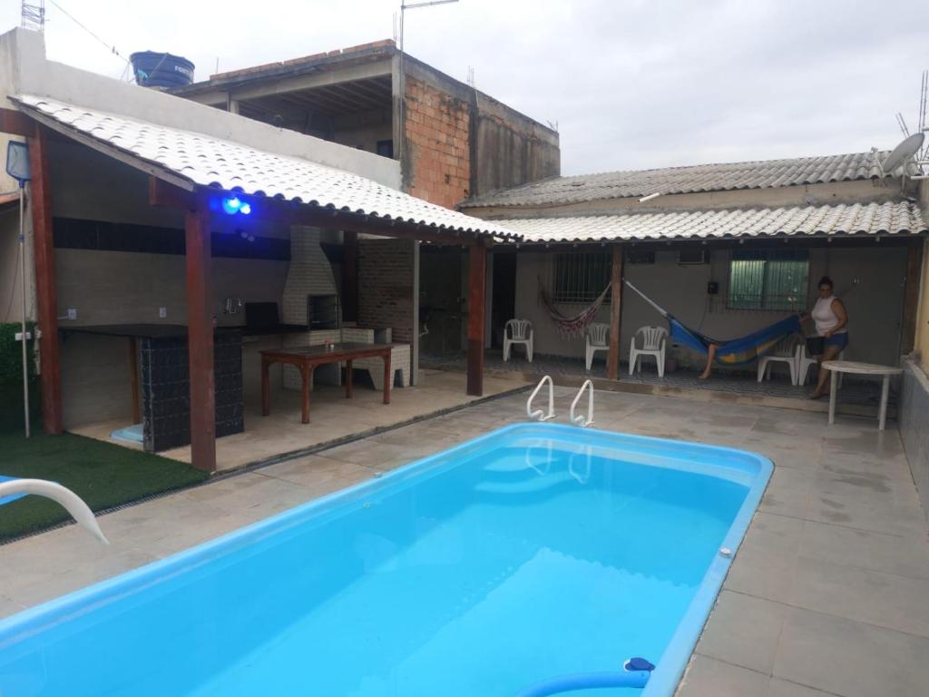 a swimming pool in front of a house with a playground at Casa raízes do bem in São Pedro da Aldeia
