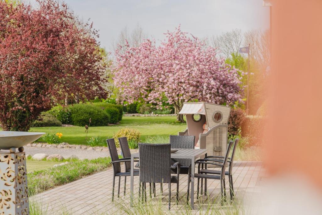 - une table et des chaises dans un jardin avec une maison ornithologique dans l'établissement Ferienhaus Dorfkiek - Bauernhof Hopp Vadersdorf, à Fehmarn