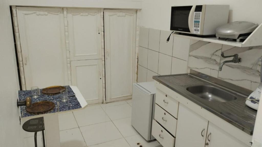 a small kitchen with a sink and a microwave at salvador, quartos com ar centro,pelourinho in Salvador
