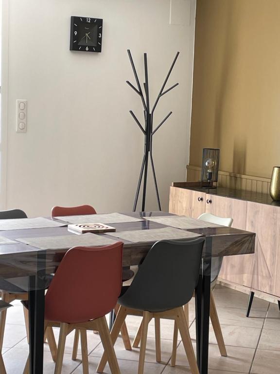 une table à manger avec des chaises et une horloge murale dans l'établissement Appartement entre Mer & Montagne, à la campagne, à Ustaritz