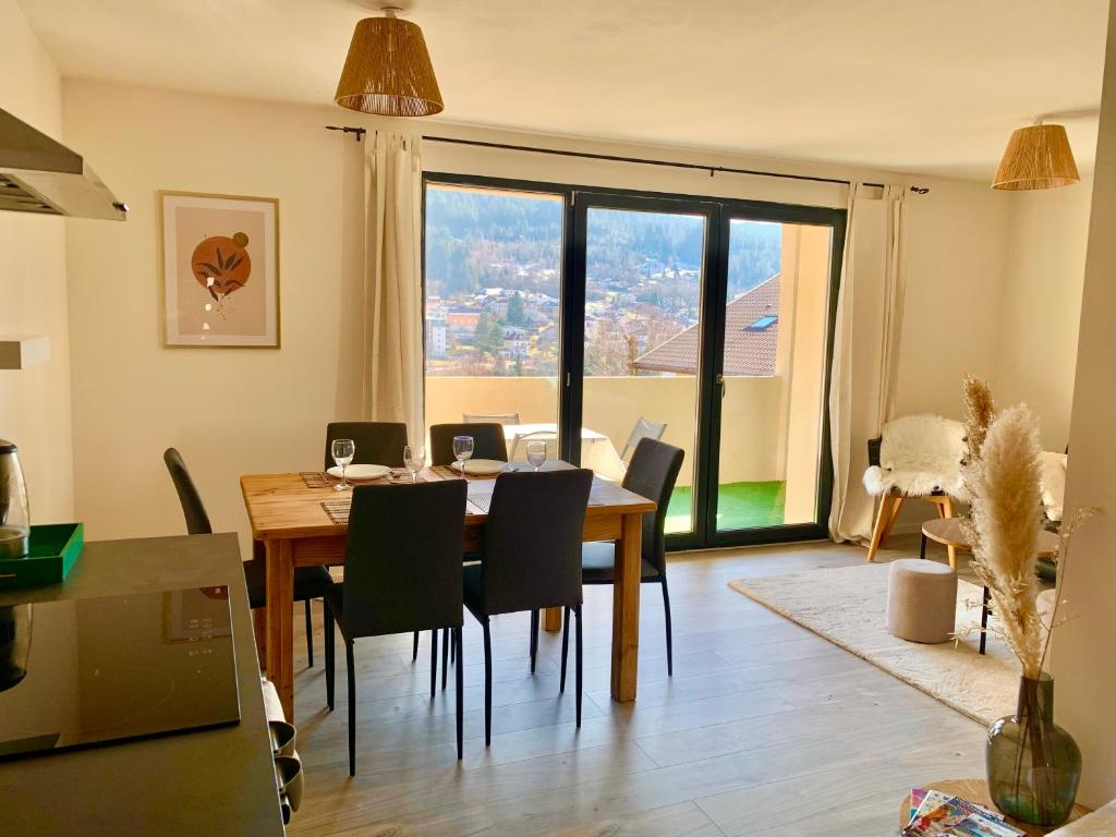 une salle à manger avec une table et des chaises et une grande fenêtre dans l'établissement La Résidence des Feutres app3 au RDC, à Gérardmer