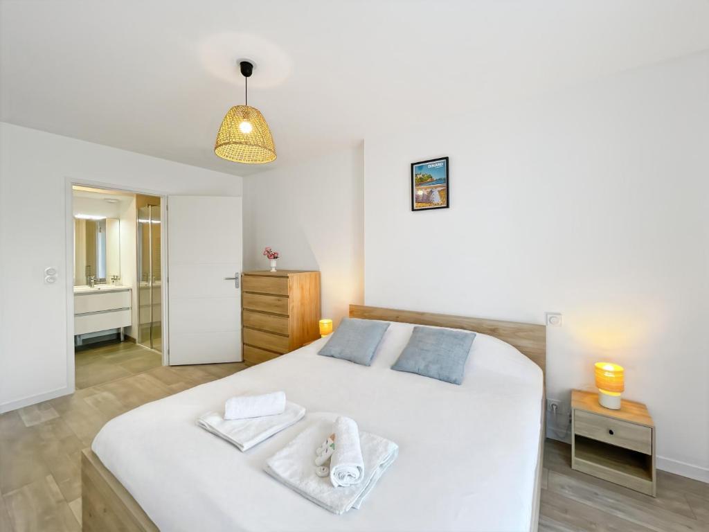 une chambre avec un lit blanc avec des serviettes dessus dans l'établissement L'échappée Belle Terrasse et Plages Saint Coulomb, à Saint-Coulomb