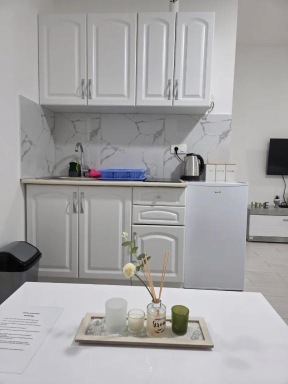 a kitchen with white cabinets and a tray with flowers at Taksim Apartman in Igalo