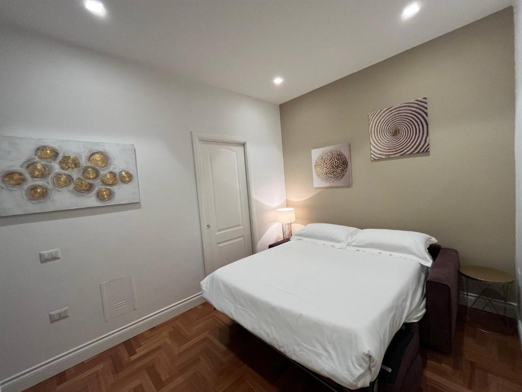 sypialnia z białym łóżkiem i obrazami na ścianie w obiekcie B&B Villa Sant'Elmo con parcheggio interno w mieście Neapol
