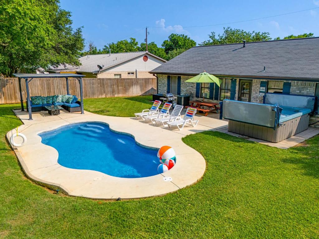 Un patio trasero con piscina y una casa. en 5 O'Clock Somewhere - Hot Tub Pool Fire Pit, en Fredericksburg