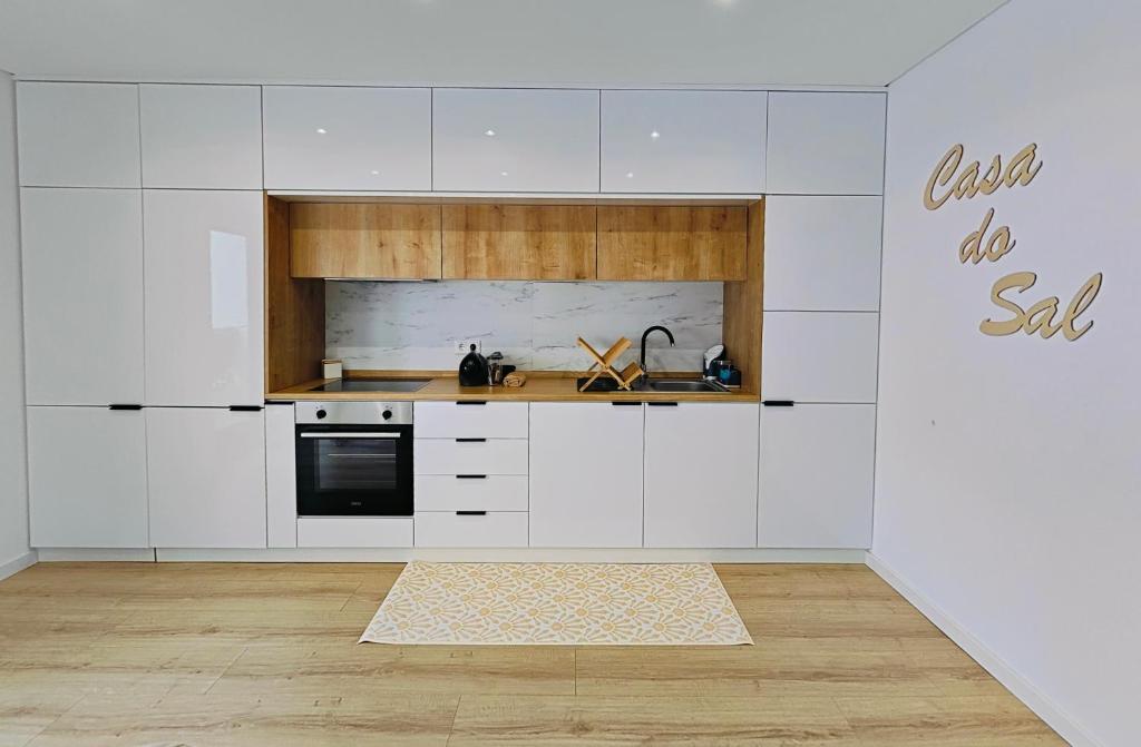 a kitchen with white cabinets and a sink at Casa do Sal in Troia