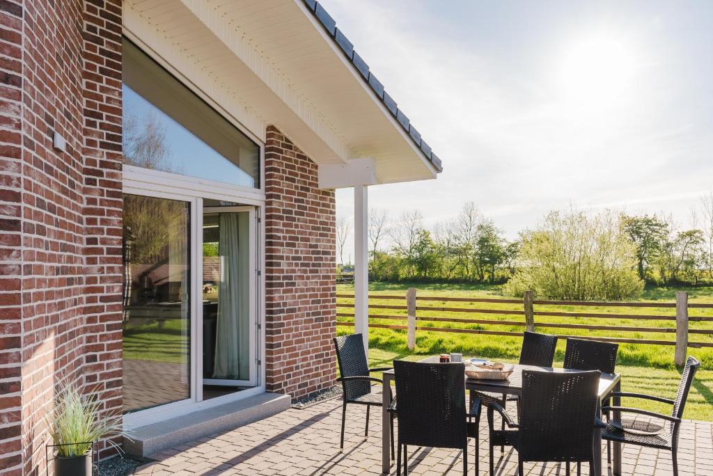 un patio avec une table et des chaises à côté d'un bâtiment dans l'établissement Ferienhaus Wiesenkiek - Bauernhof Hopp Vadersdorf, à Fehmarn