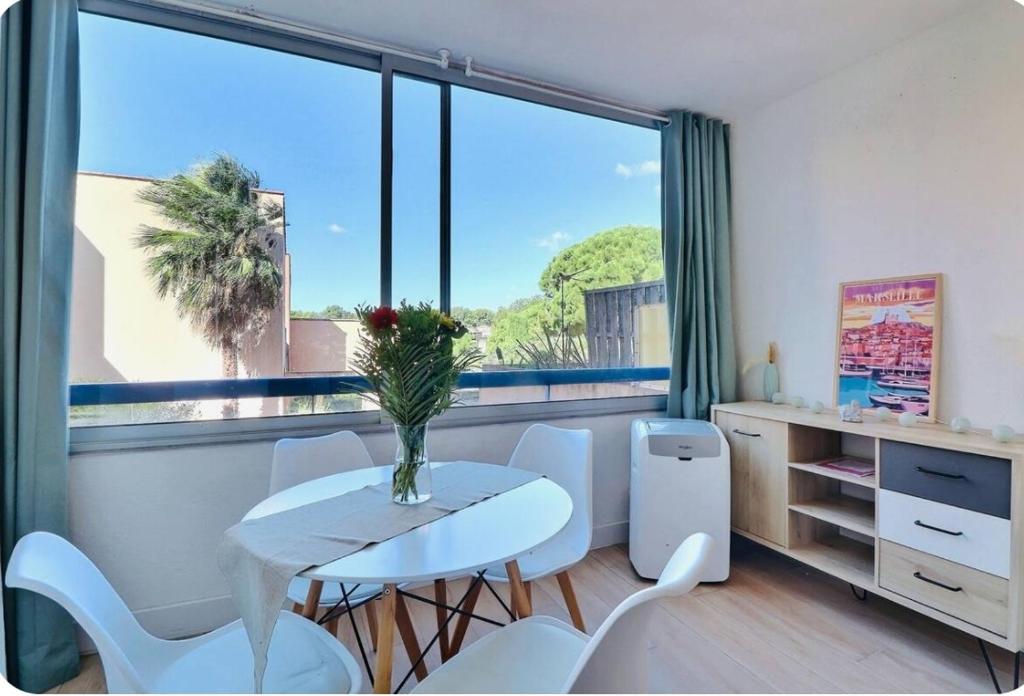 - une table et des chaises blanches dans une chambre dotée d'une grande fenêtre dans l'établissement Appartement Instant Cozy Proche Mer avec Parking, à La Ciotat