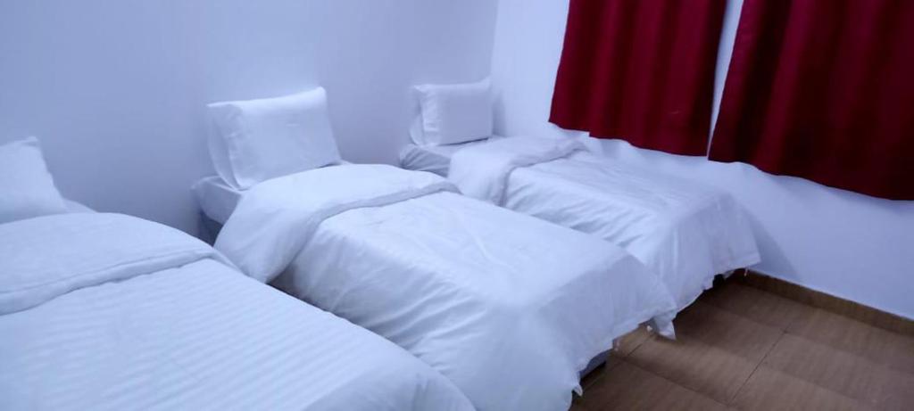 a room with four white beds and a red curtain at Elias Hotel2 نزل الياس in Al Madinah