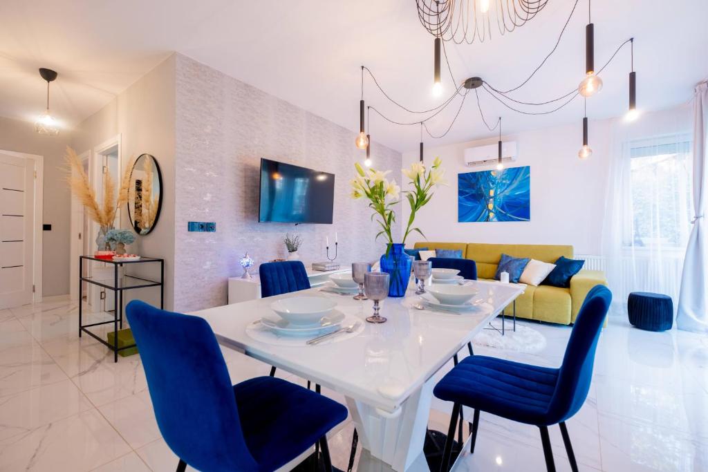 a dining room and living room with a white table and blue chairs at White Rose Hill Luxury Apartment Budapest in Budapest