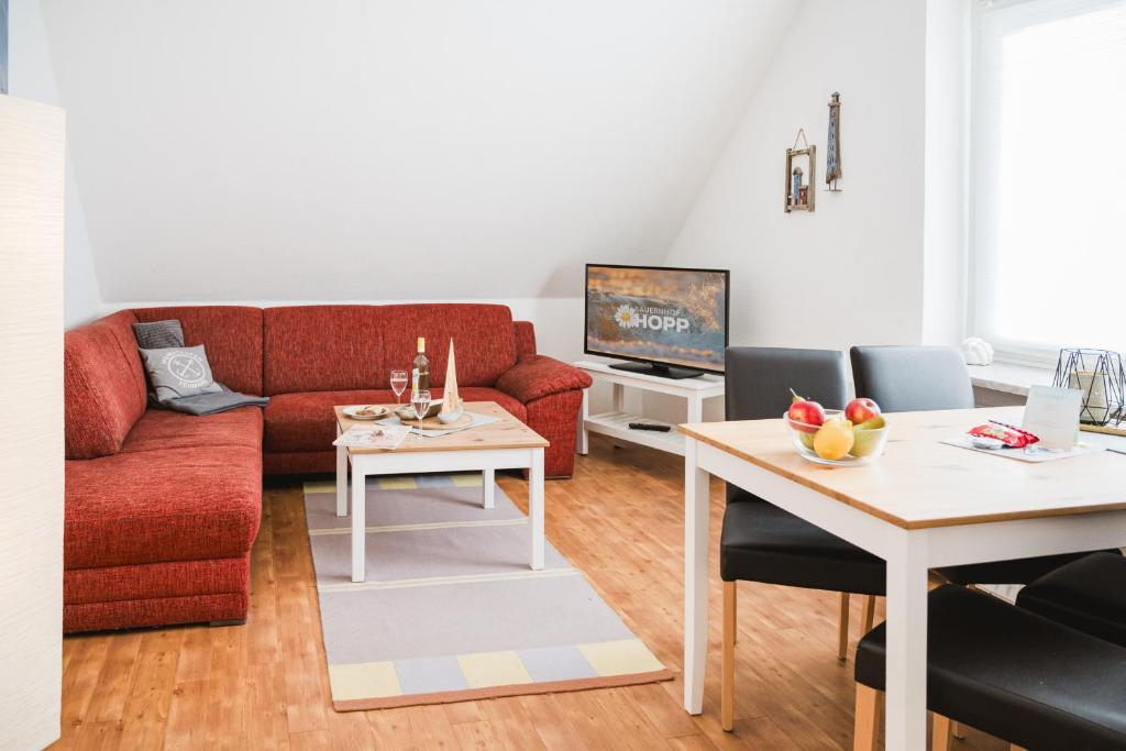 un salon avec un canapé rouge et une table dans l'établissement Landhaus Ferienwohnung 1 - Bauernhof Hopp Vadersdorf, à Fehmarn