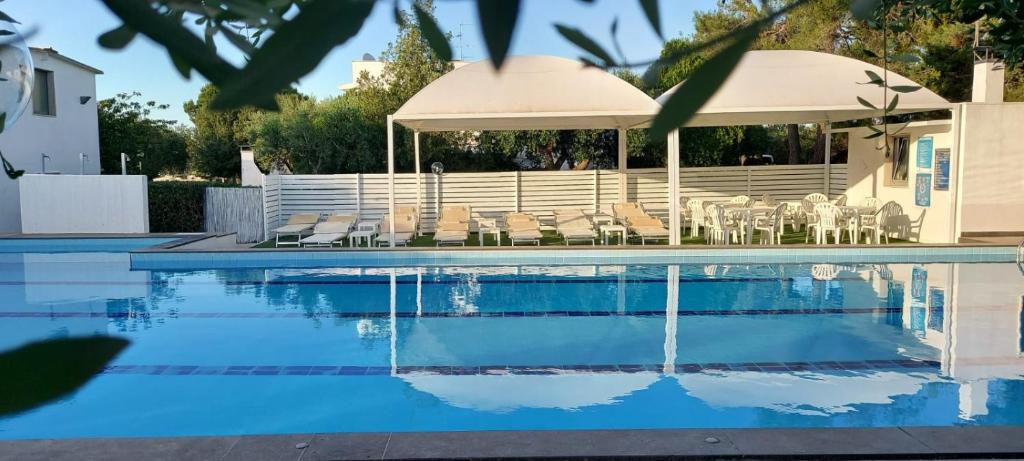 a swimming pool with chairs and an umbrella at Pets under the Sun in Alberobello